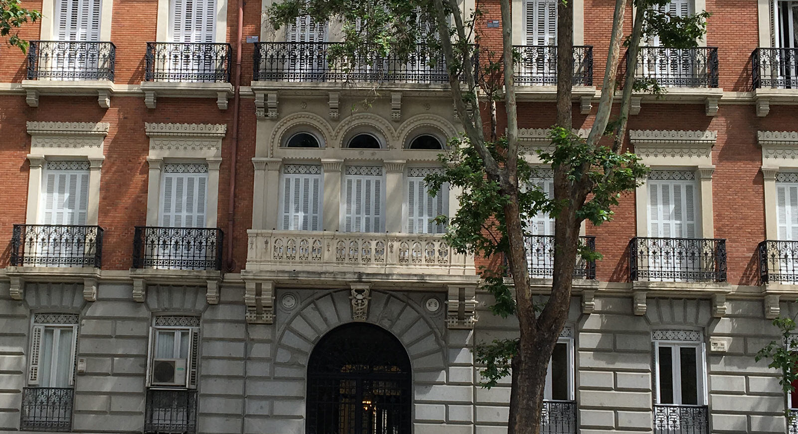 Red-brick facade with wrought-iron balconies of the Madrid office on Calle Serrano
